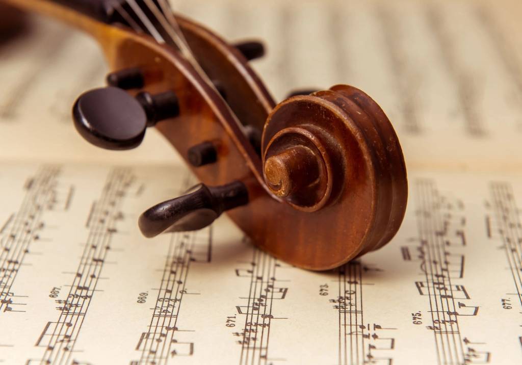Close-up of violin scroll resting on sheet music.