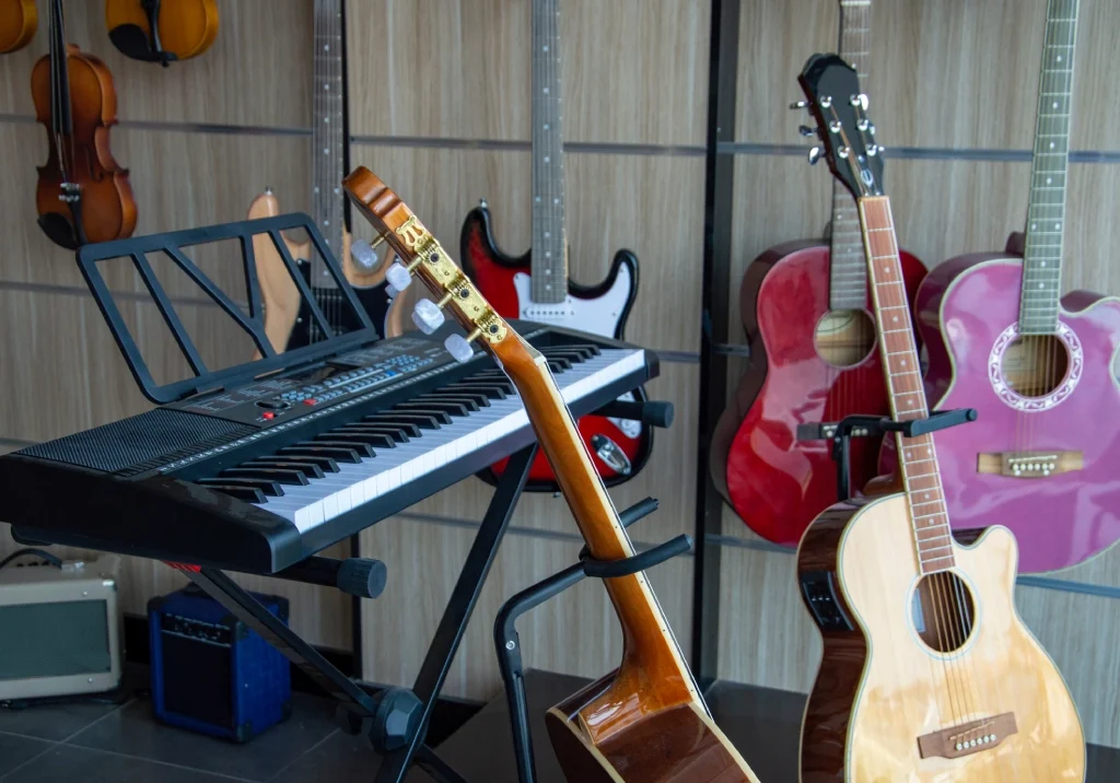 A variety of musical instruments including guitars and a keyboard in a storage space.